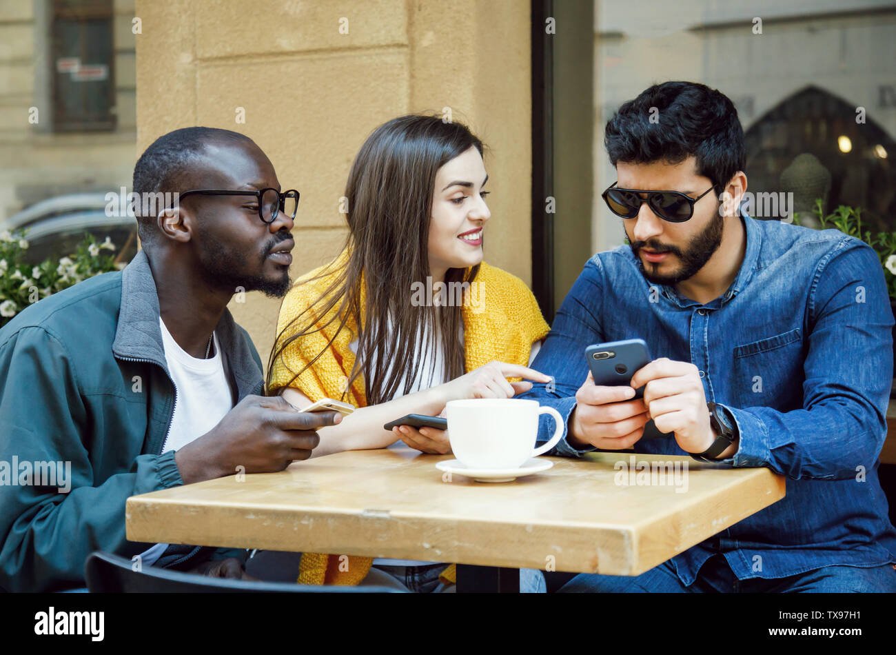 Tre felice multiculturale amici chiacchierare insieme all'outdoor cafe Foto Stock