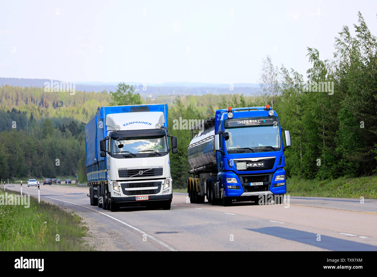 Jamsa, Finlandia. Il 6 giugno 2019. Blue Man semi tanker passa un altro carrello guida in salita su autostrada. Carrelli elevatori con carico pesante possono essere molto più lento in salita. Foto Stock