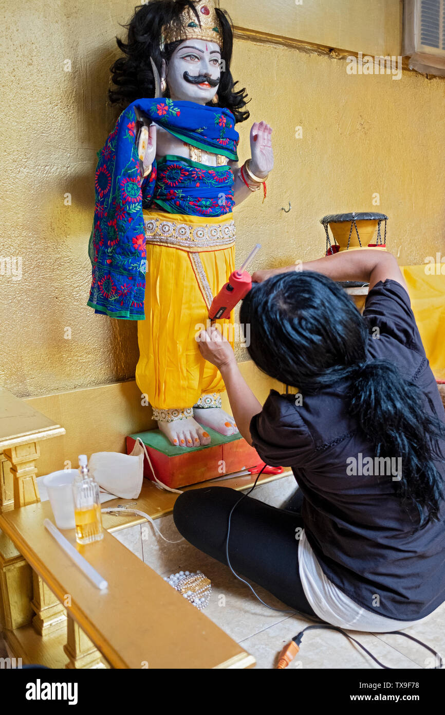 Una fervente adoratore indù mette nuovi vestiti su una statua del dio Muneeswaran a un tempio nel Queens, a New York City. Foto Stock