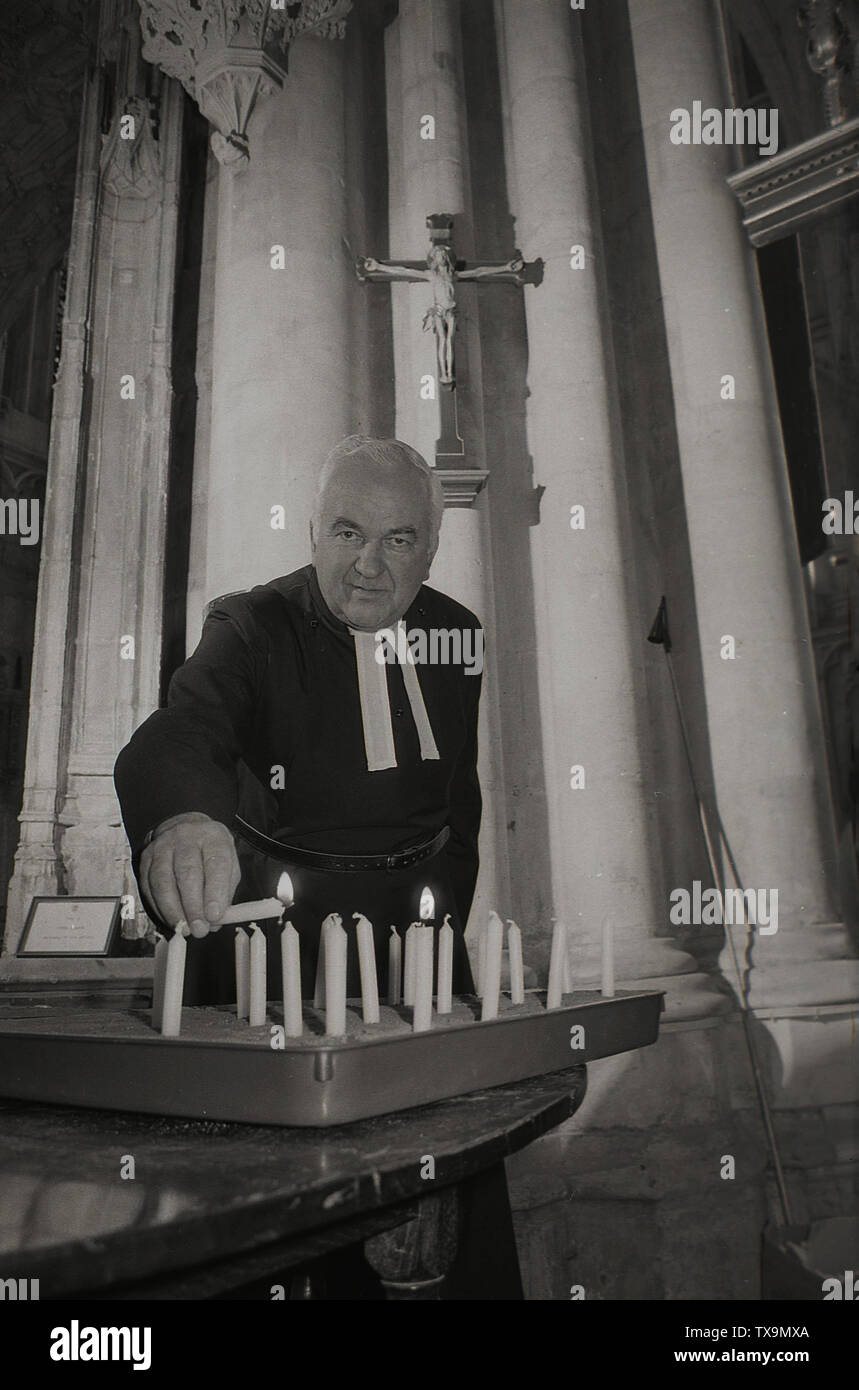 1985, un sacerdote accendendo candele in una chiesa, Inghilterra, Regno Unito. Foto Stock