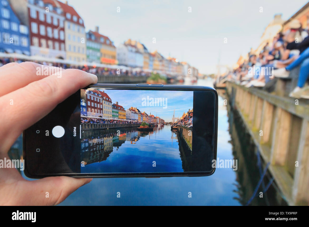 Uomo caucasico catturare foto di Nyhavn a Copenaghen durante Sankthans fest celebrazione Foto Stock