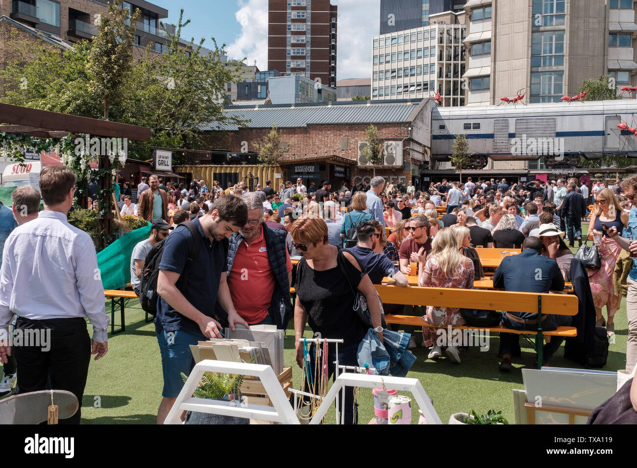 Regno Unito,Londra- persone mangiare fuori in una giornata di sole .Aceto cantiere è un giardino urbano aperto sette giorni a settimana, con bancarelle prodotti alimentari, abbigliamento vintage e di antiquariato t Foto Stock