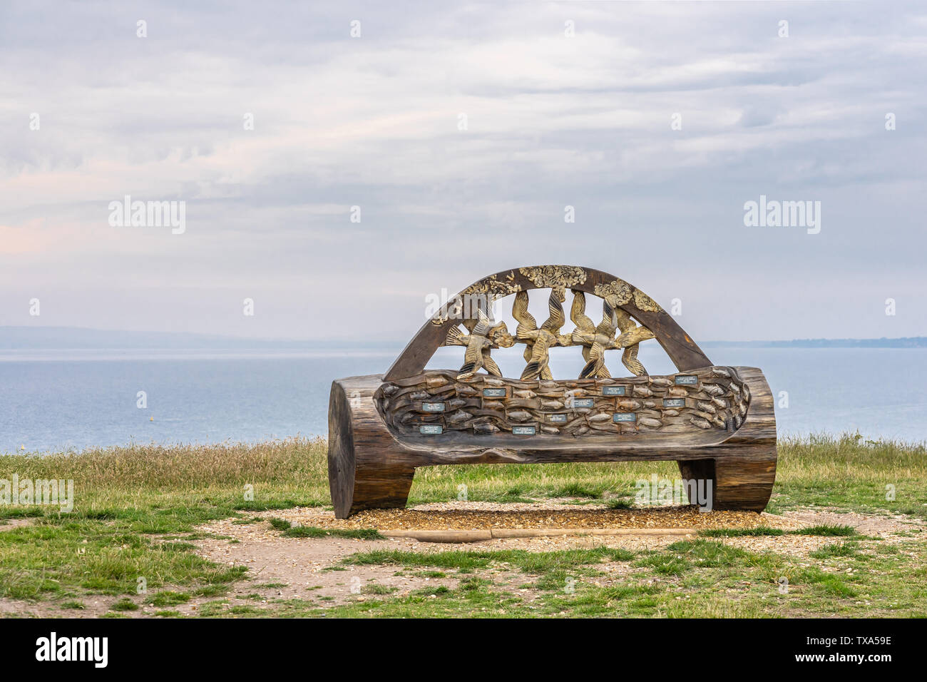 Legno scolpito memorial panca sulla cima della collina di Warren a testa Hengistbury nel Dorset, England, Regno Unito Foto Stock