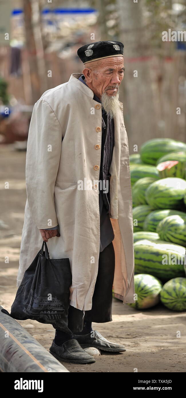 Uyghur oldman pensieroso ad un'asta di vendita di velon. Mercato Zootecnico-Hotan-Xinjiang-Cina-0191 Foto Stock