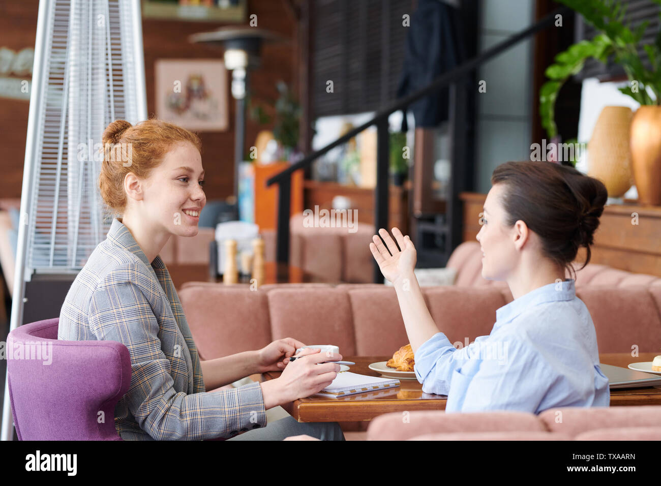 Giovani donne che condividono idee durante il pranzo Foto Stock