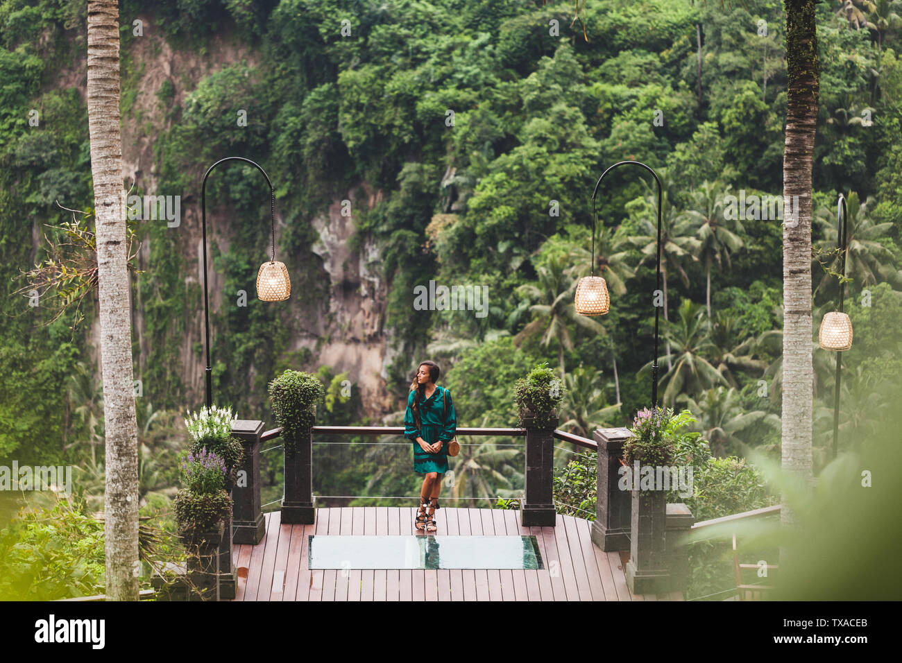 Asian brunette donna in abito verde sul balcone con straordinaria vista Giungla dalla scogliera in Ubud, Bali Foto Stock