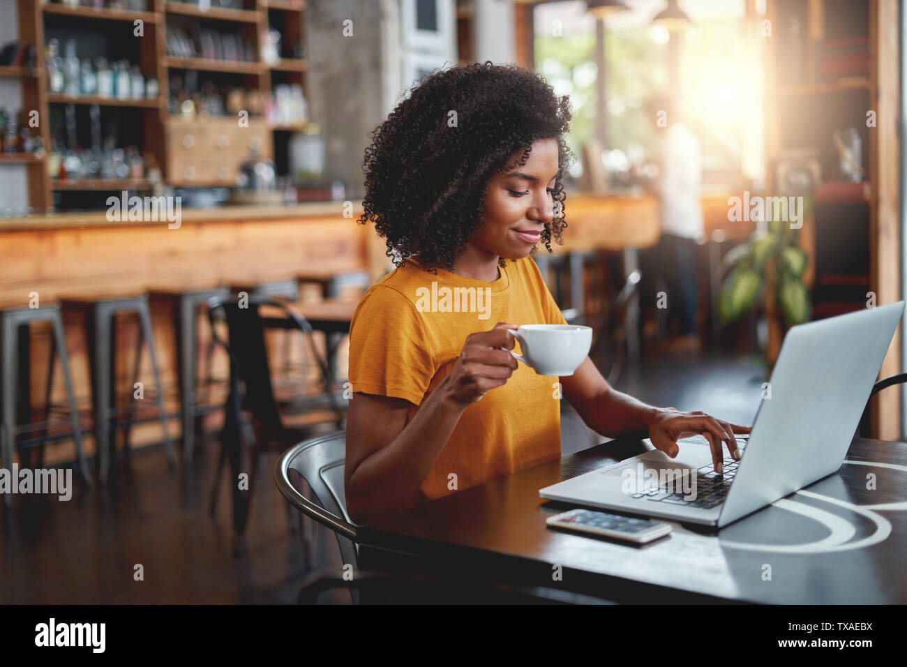 Giovane donna coppa di ritegno in mano utilizzando laptop Foto Stock