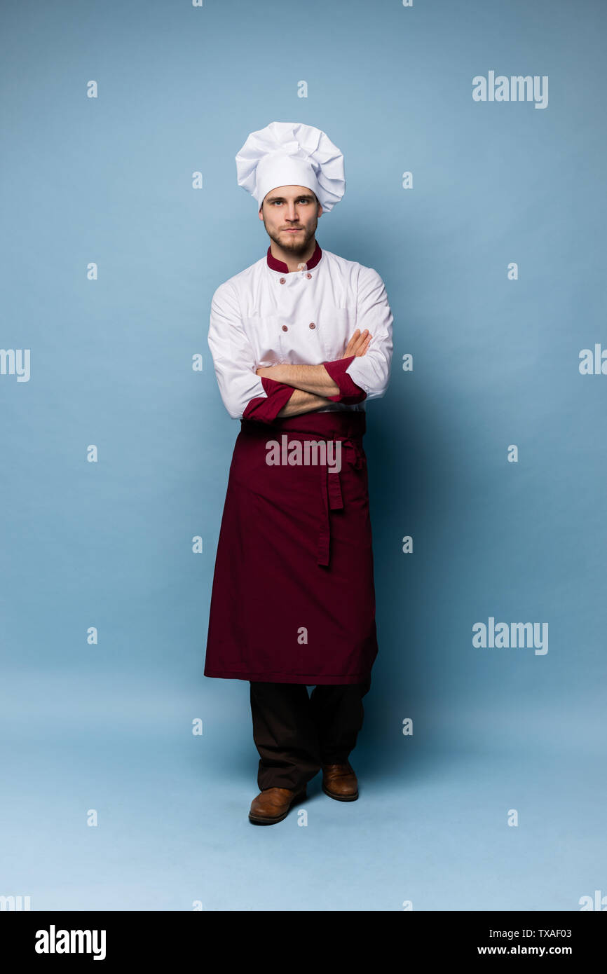 A piena lunghezza Ritratto di Allegro gioioso chef cucinare con la stoppia in berretto e vestito di bianco guardando la telecamera isolato Foto Stock