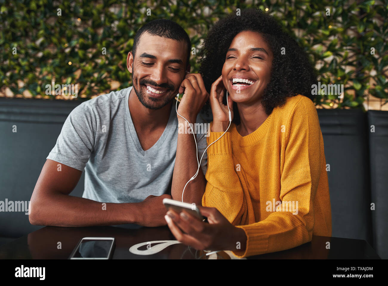 Coppia giovane la condivisione di cuffie per ascoltare la musica sul cellulare phon Foto Stock