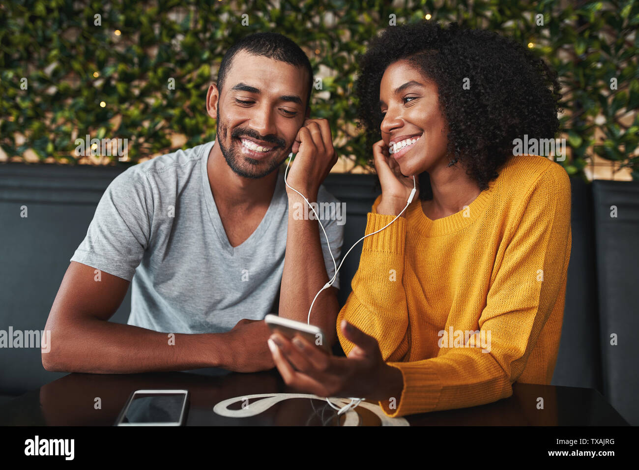 Coppia insieme ascoltando musica in café Foto Stock