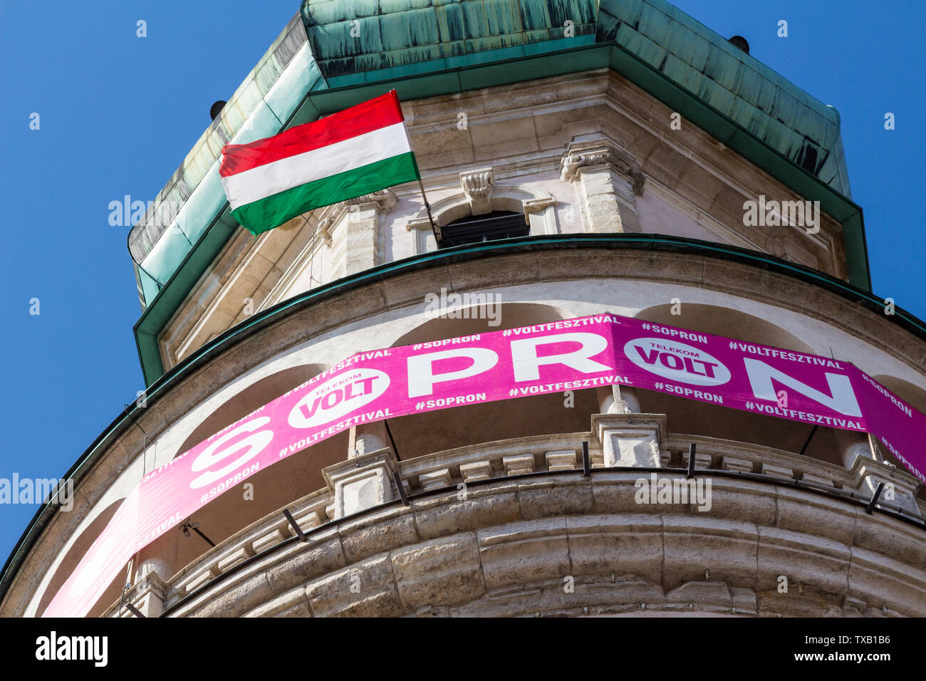 Rosa banner di Telekom di Festival Volt fissato sulla torre Firewatch in Sopron, Ungheria. Close-up con bandiera ungherese. Foto Stock