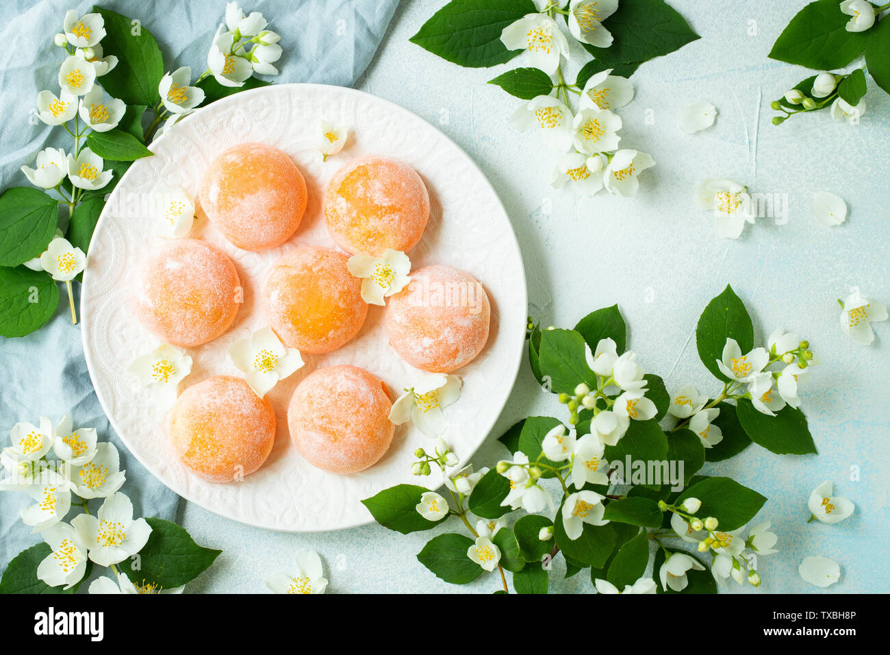 Multi-colore di giapponese gelato Mochi in impasto di riso e fiori di gelsomino su un concreto sfondo blu. Tradizionale Giapponese del dessert su una piastra bianca. Foto Stock