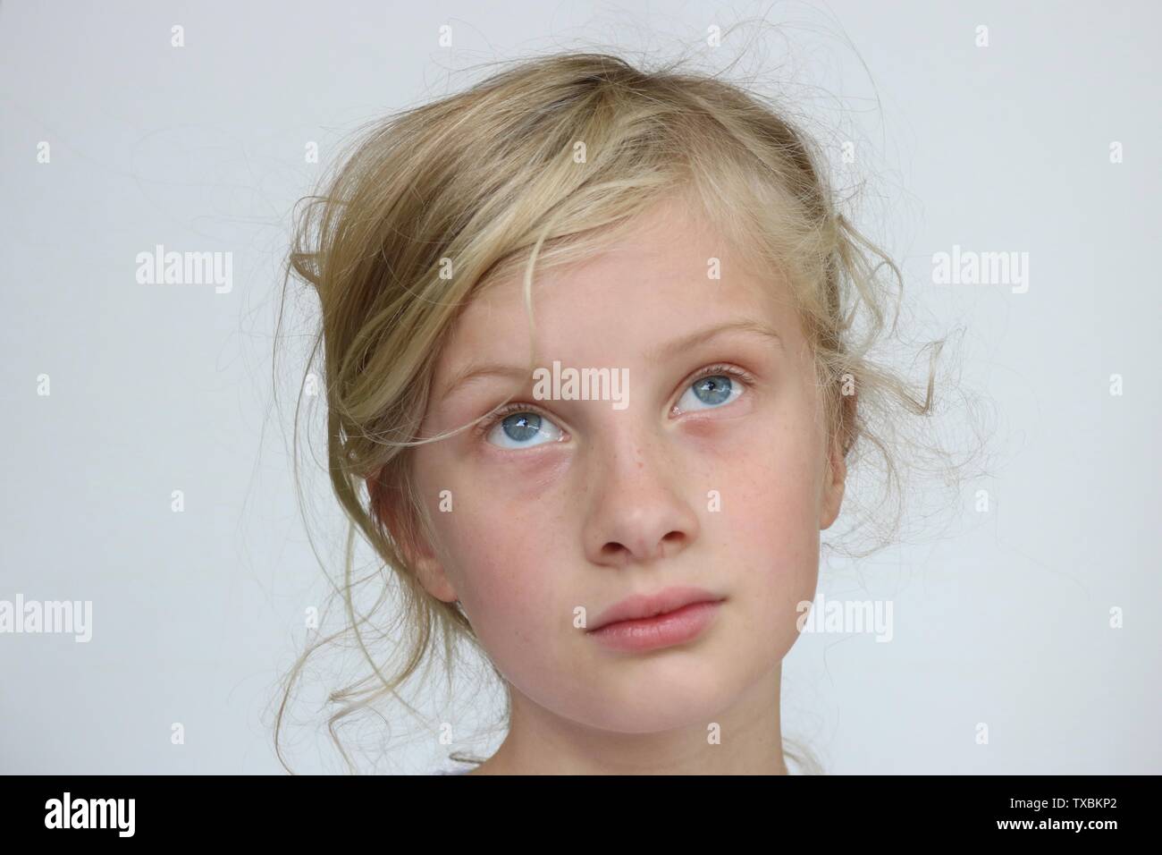 Ritratto di un giovane biondo dagli occhi blu ragazza cercando di pensare contro uno sfondo bianco Foto Stock