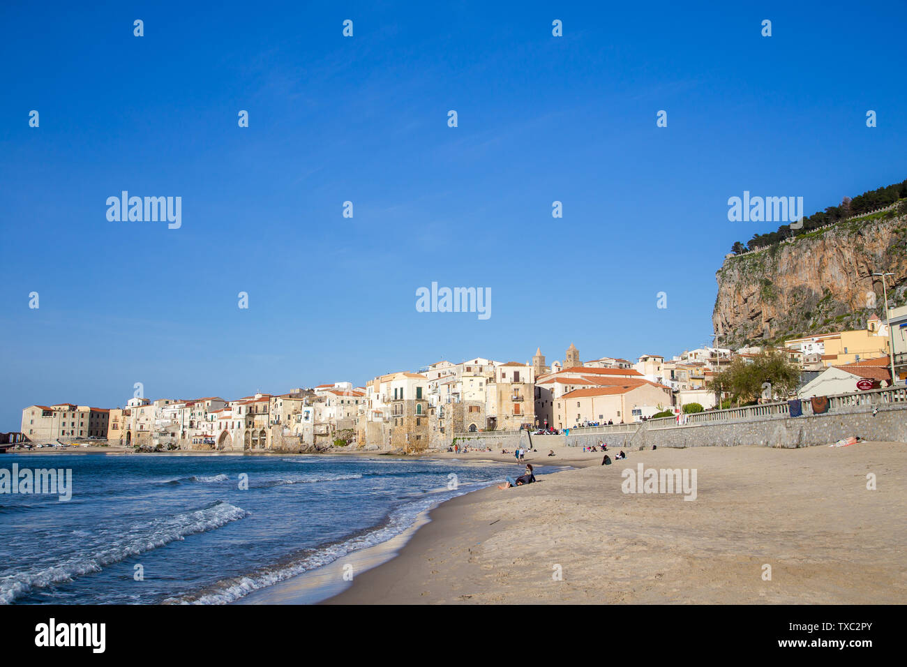 Céfalu, Sicilia, Italia - 16 Marzo 2018: una rilassante giornata di sole sulla spiaggia di Céfalu, con poche persone irriconoscibili e vecchi edifici tipici Foto Stock