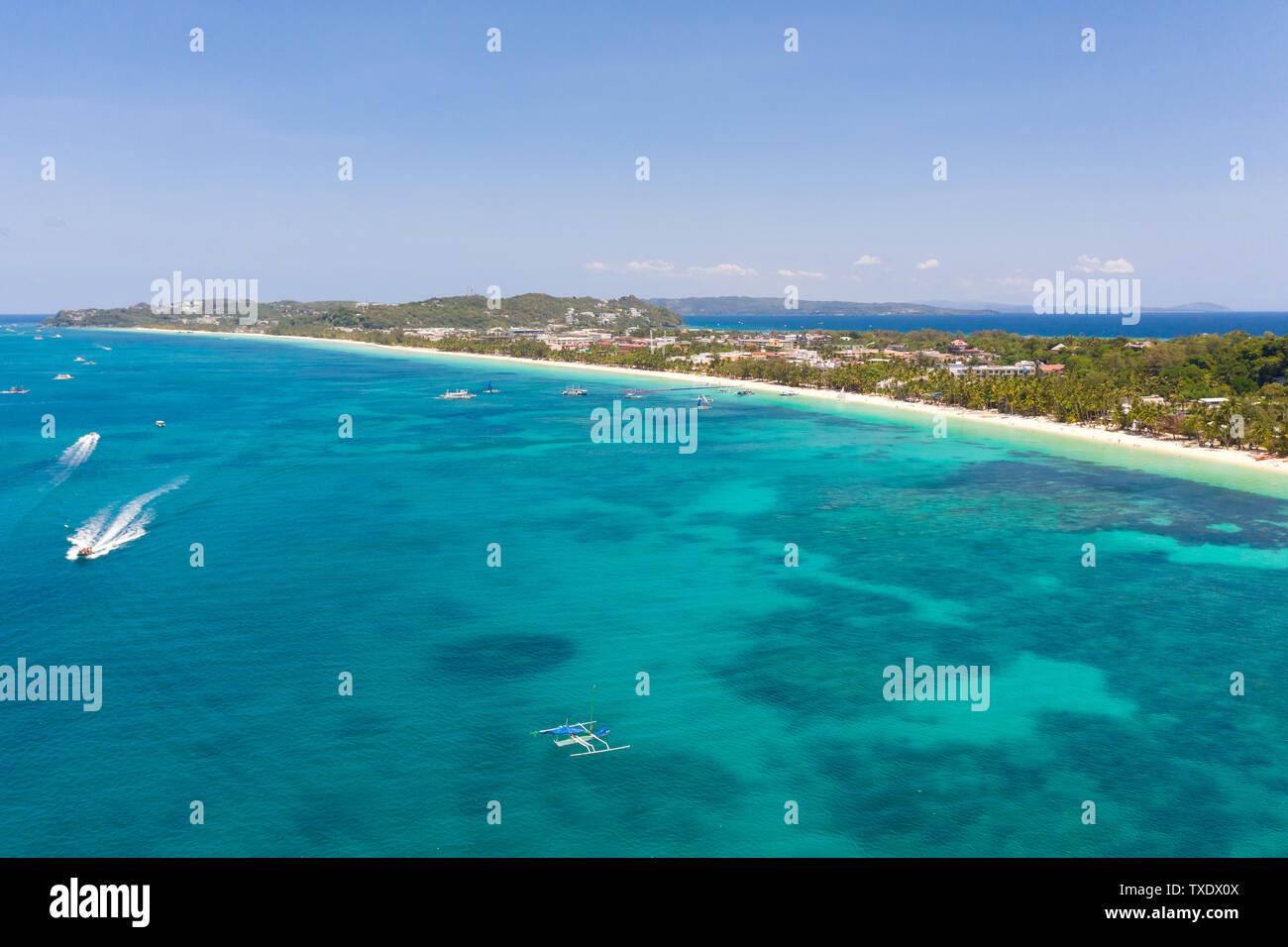 Seascape nelle Filippine in tempo soleggiato, vista da sopra. Mare trasparente e le imbarcazioni turistiche nei pressi dell'isola di Boracay. Edifici residenziali e alberghi sulla Big Island. Foto Stock