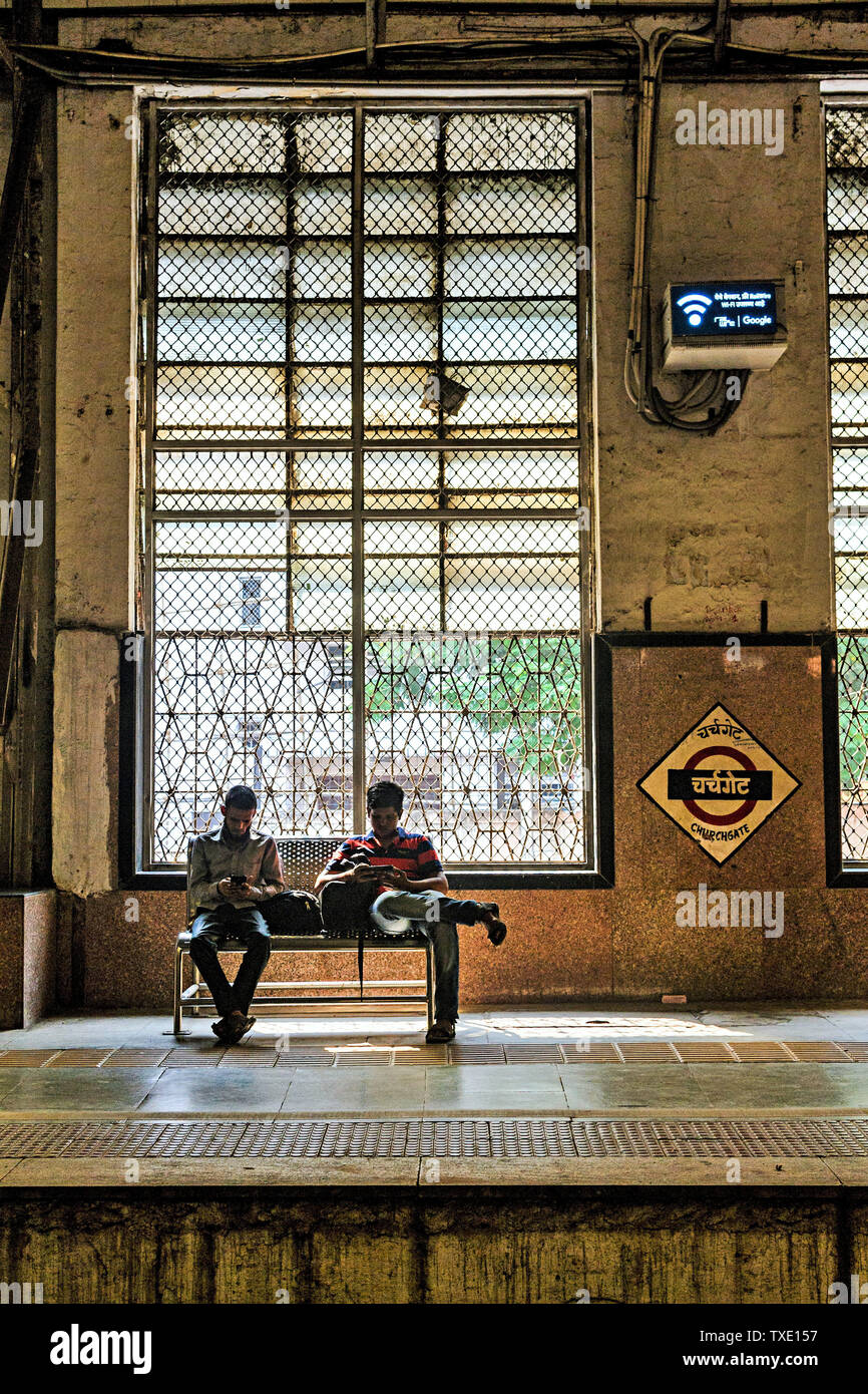 Gli uomini seduti sul banco, Chiesa di gate stazione ferroviaria, Mumbai, Maharashtra, India, Asia Foto Stock