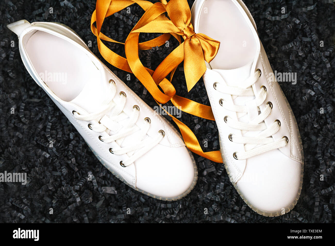 Sneakers bianco e giallo di prua sono giacenti su texture di sfondo nero. Foto Stock