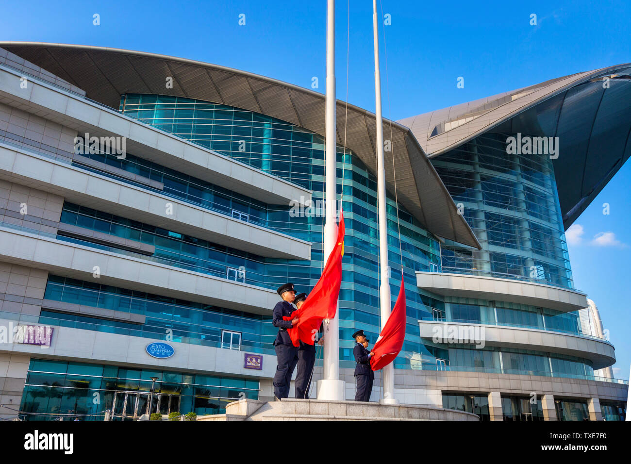 La polizia alzando la bandiera cinese al di sopra della Hong Kong bandiera alla cerimonia quotidiana, Centro Congressi ed Esposizioni di Hong Kong SAR, Cina Foto Stock