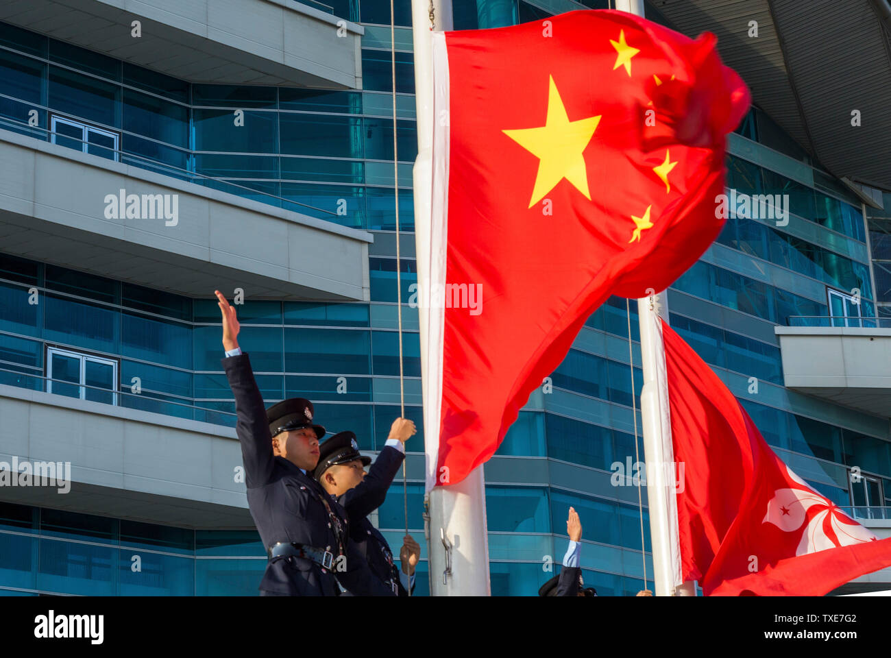 La polizia alzando la bandiera cinese al di sopra della Hong Kong bandiera alla cerimonia quotidiana, Centro Congressi ed Esposizioni di Hong Kong SAR, Cina Foto Stock