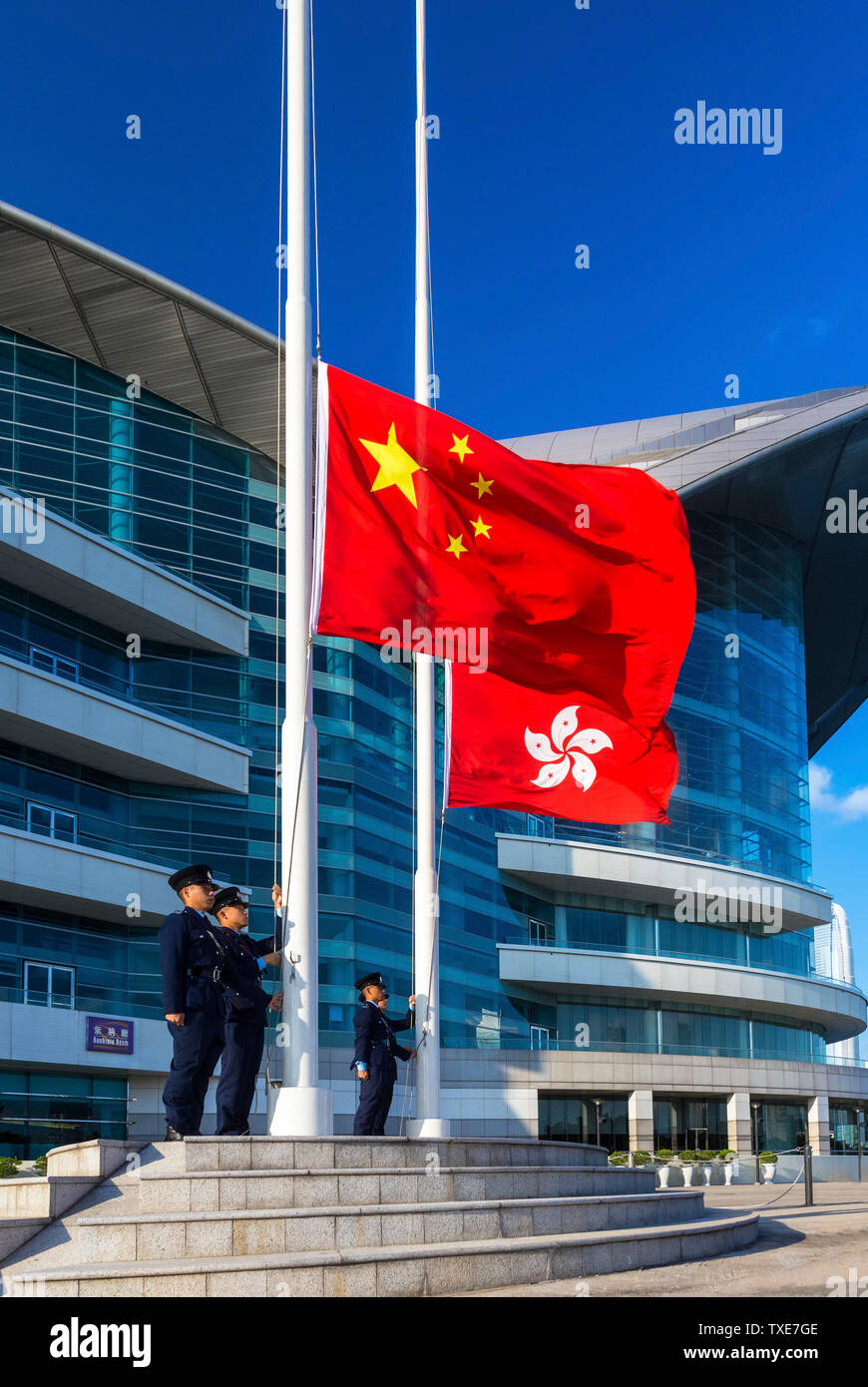 La polizia alzando la bandiera cinese al di sopra della Hong Kong bandiera alla cerimonia quotidiana, Centro Congressi ed Esposizioni di Hong Kong SAR, Cina Foto Stock