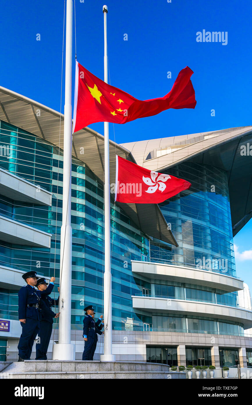 La polizia alzando la bandiera cinese al di sopra della Hong Kong bandiera alla cerimonia quotidiana, Centro Congressi ed Esposizioni di Hong Kong SAR, Cina Foto Stock