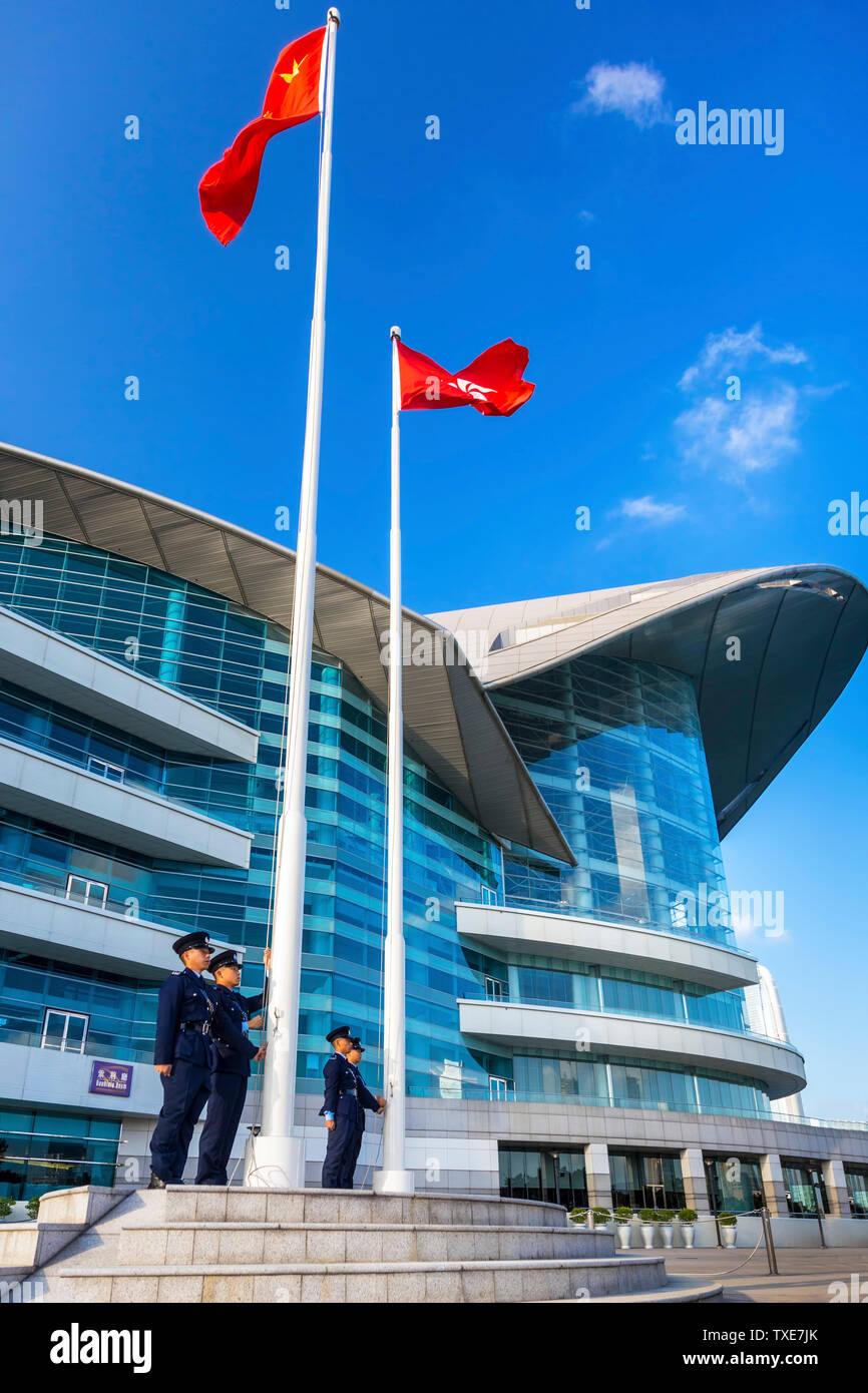 La polizia alzando la bandiera cinese al di sopra della Hong Kong bandiera alla cerimonia quotidiana, Centro Congressi ed Esposizioni di Hong Kong SAR, Cina Foto Stock