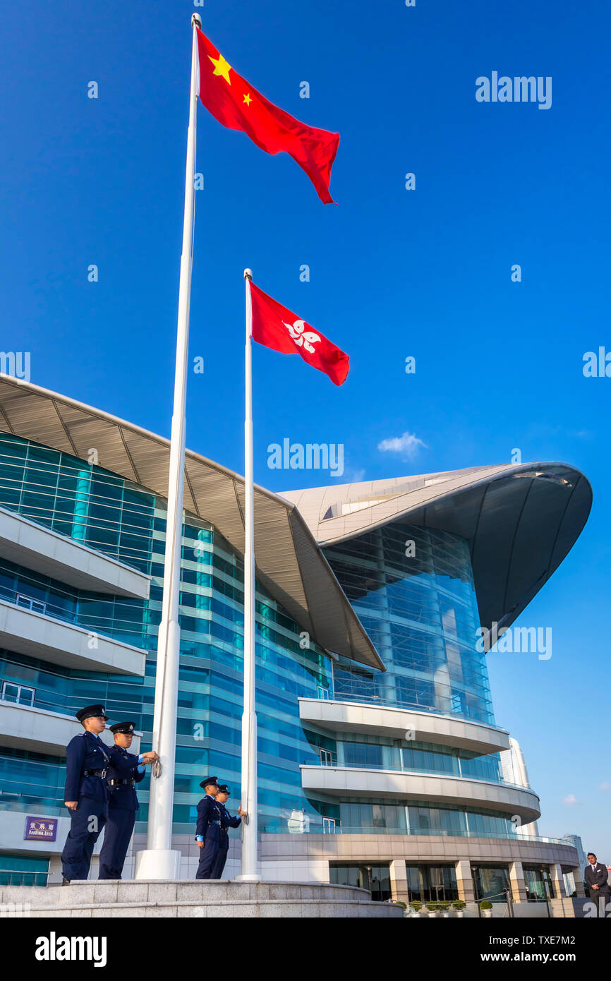 La polizia alzando la bandiera cinese al di sopra della Hong Kong bandiera alla cerimonia quotidiana, Centro Congressi ed Esposizioni di Hong Kong SAR, Cina Foto Stock