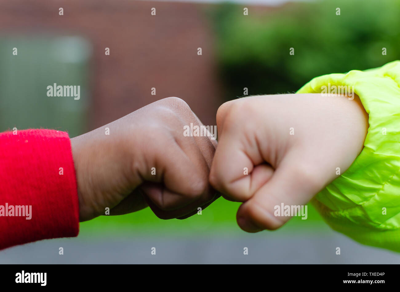 Due bambini di diverse razze e colore della pelle si salutano con pugno bump. Mostra fotografica di amicizia, supporto, uguaglianza e diversità. Foto Stock