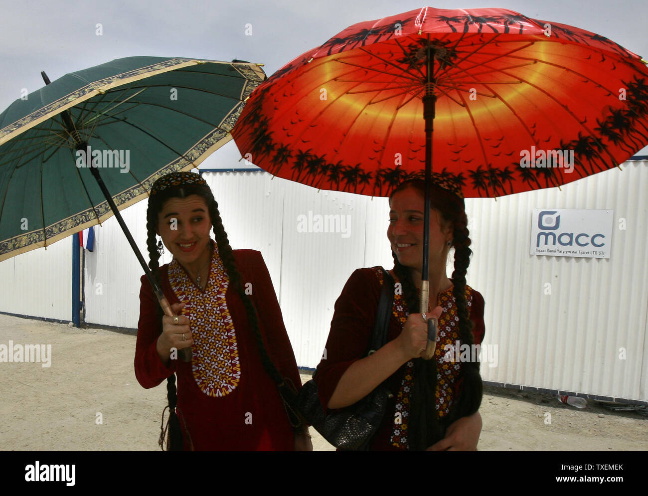 Giovani donne turkmene utilizzare ombrelloni per raffreddare se stessi in +40 C (104 F) meteo Aşgabat, Turkmenistan il 11 maggio 2007. Secondo una legge fatta dall ex Presidente turkmeno Saparmurat Niyazov a tutte le donne del paese deve indossare abiti lunghi. (UPI foto/Anatoli Zhdanov) Foto Stock