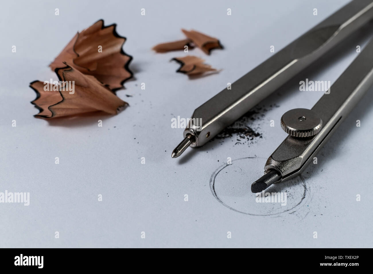 Macro Closeup dettaglio di una geometria di bussola a matita e matita affilatura di trucioli di legno su carta bianca con un cerchio disegnato - Concetto di istruzione scolastica Foto Stock