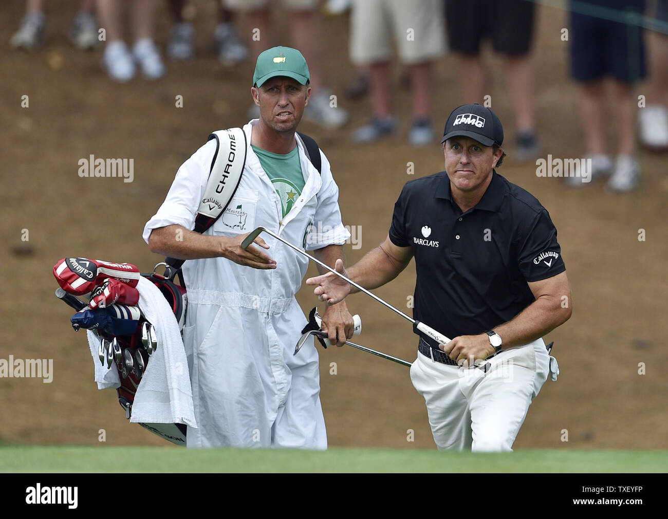 Caddie Jim "Ossa" Mackay mani Phil Mickelson il suo putter dopo Phil chip su al decimo verde nel secondo round del 2015 Masters a Augusta National Golf Club di Augusta, in Georgia il 10 aprile 2015. Foto di Kevin Dietsch/UPI Foto Stock