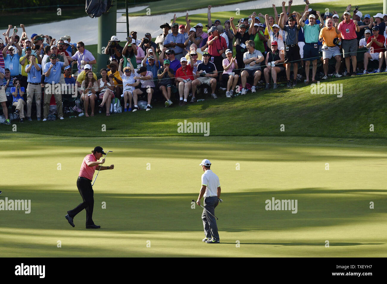 Patroni e Paul Casey di Inghilterra guarda Phil Mickelson celebrare dopo che egli compie un lungo putt per il birdie il sedicesimo foro nel terzo round del 2015 Masters a Augusta National Golf Club a Augusta, in Georgia il 11 aprile 2015. Foto di Kevin Dietsch/UPI Foto Stock