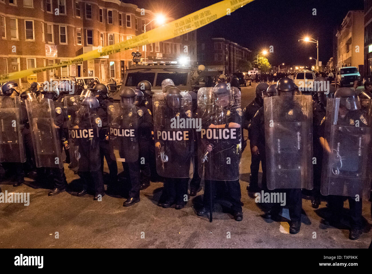 La polizia di tumulto linea di marcia fino con militare veicolo di soccorso mentre i cittadini locali spinto al limite del 10 p.m. coprifuoco a Baltimore, Maryland il 28 aprile 2015. Le proteste hanno eruttato dopo la morte di Freddie grigio. Foto di Ken Cedeño/UPI Foto Stock