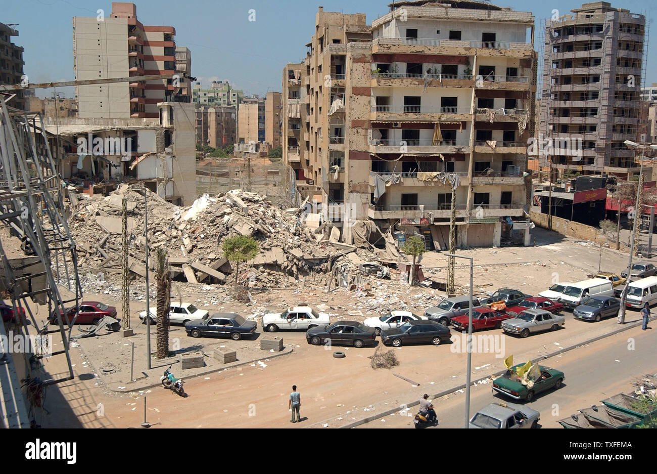 I residenti della periferia sud passa un edificio bombardato come loro capo per la casa a Beirut la periferia sud ore dopo un'U.N. mediate il cessate il fuoco è entrato in effetti il 14 agosto 2006. Dopo il cessate il fuoco entrato in vigore alle 08:00 (05:00 GMT) Ora locale di decine di migliaia di profughi libanesi confezionato le loro cose e diretti verso le loro case nel sud del Libano. (UPI foto/Norbert Schiller) Foto Stock