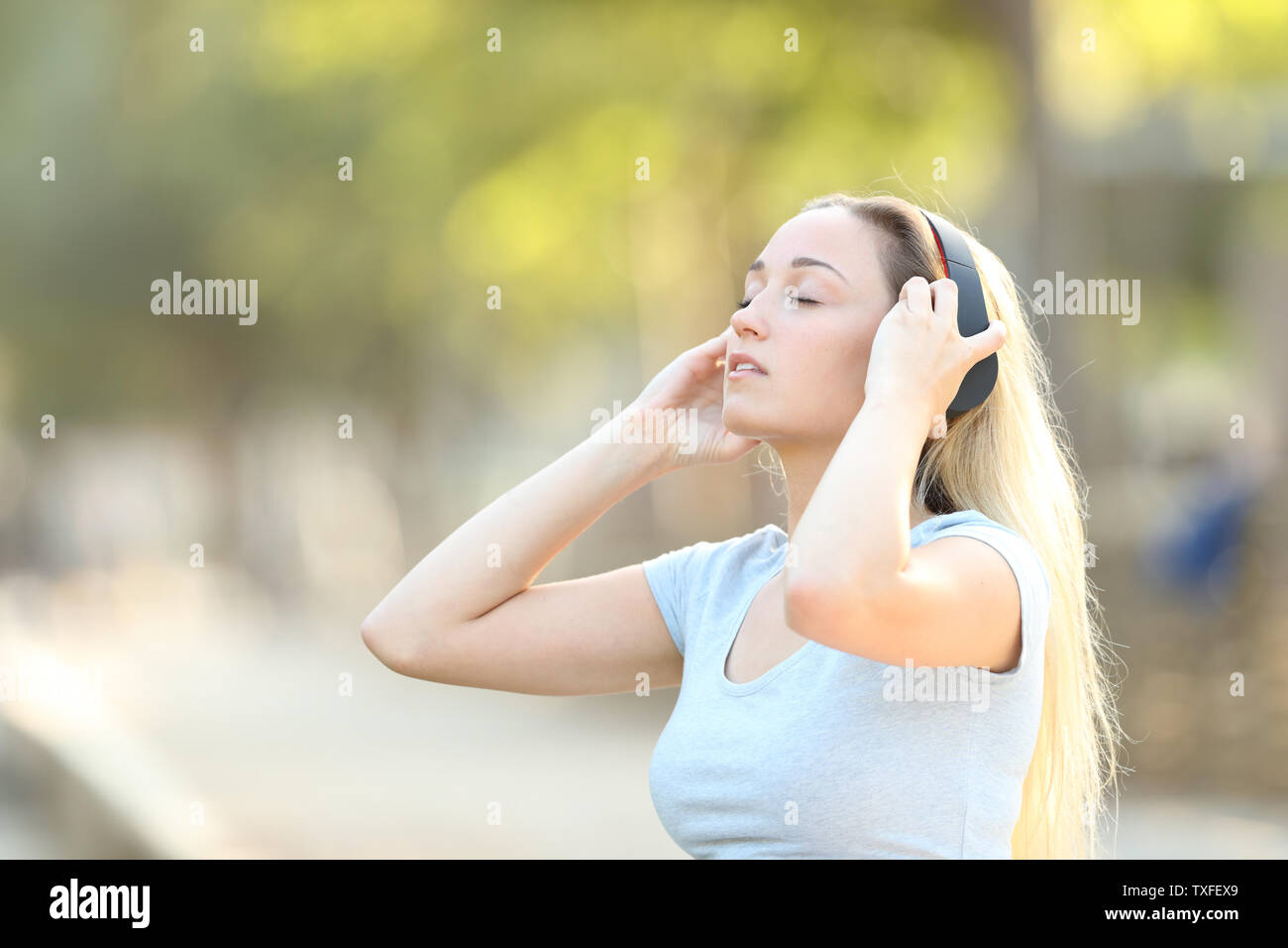 Adolescente mettendo le cuffie wireless per ascoltare la musica in un parco Foto Stock