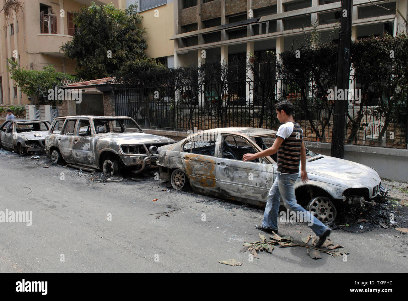 Un uomo cammina passato bruciato auto come scontri tra governo pro e il led di Hezbollah opposizione continuano per tutto il Libano per un secondo giorno di lasciare molte parti di Beirut e di altri villaggi e città deserte mercoledì 8 maggio 2008. Un generale sciopero del lavoro che è stato chiamato per ieri ha speso in scontro armato tra i due gruppi. La gran parte del territorio del paese è tagliato e l'aeroporto rimane chiuso. UPI (foto) Foto Stock