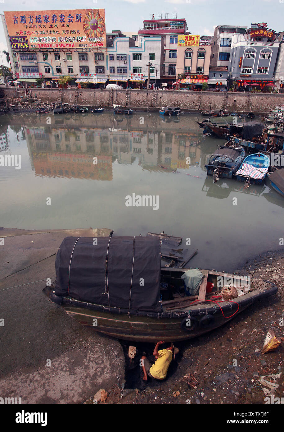 Un pescatore cinese ripara la sua piccola barca prima della notte di alta marea lava in un piccolo porto protetto nei pressi di Beihai, una città costiera nel sud della provincia di Guangxi, Cina sul confine del Vietnam il 30 agosto 2014. Benché la Cina abbia rafforzato rapidamente la propria economia attraverso il commercio internazionale, è ancora considerata un paese in via di sviluppo a causa del fatto che la maggior parte dei cinesi hanno un basso tenore di vita rispetto a paesi sviluppati. UPI/Stephen rasoio Foto Stock