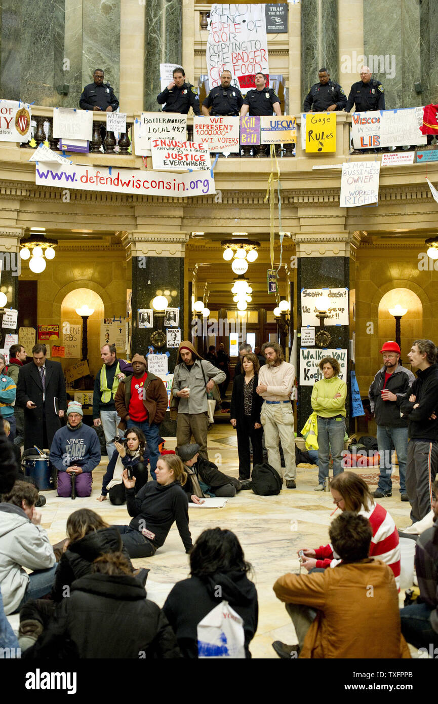 Manifestanti stand nella rotunda come guardia di polizia al secondo piano presso il Campidoglio il 1 marzo 2011 a Madison, Wisconsin. Un giudice ha ordinato il martedì che il Campidoglio dovrebbe essere aperto al pubblico " durante le ore lavorative e a volte quando questioni governative, come le audizioni, sessioni di ascolto e la corte gli argomenti sono condotte." Sebbene i manifestanti, occupando il Campidoglio per quindici giorni, non sono stati costretti a lasciare il pubblico è stato impedito di entrare l'edificio poiché esso chiuso a 4 p.m. domenica. UPI/Brian Kersey Foto Stock