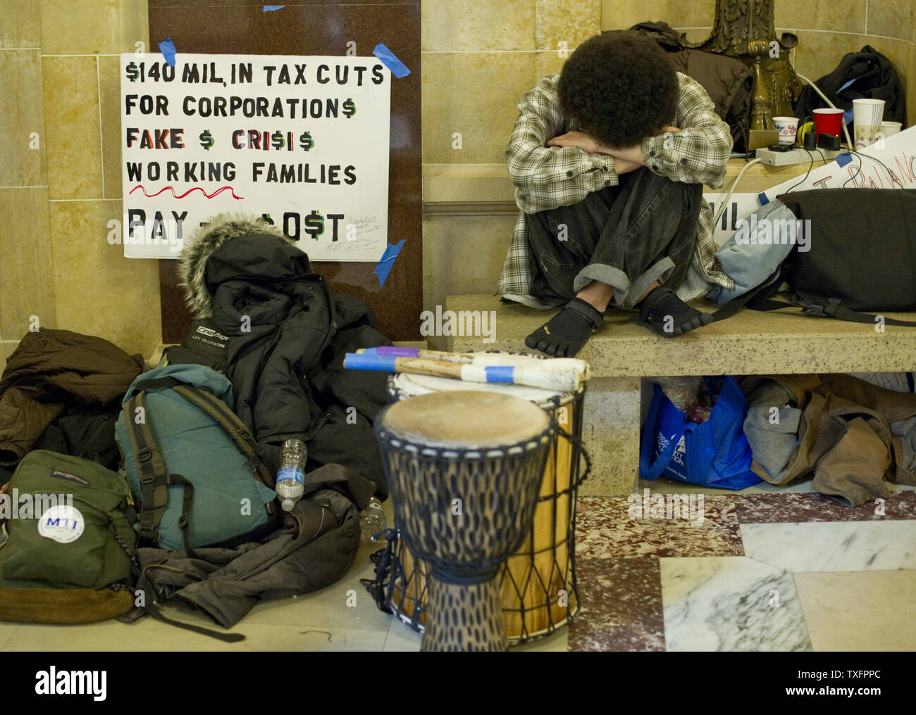 Protester Damon Terrell poggia la sua testa su un banco in Campidoglio il 1 marzo 2011 a Madison, Wisconsin. Un giudice ha ordinato il martedì che il Campidoglio dovrebbe essere aperto al pubblico " durante le ore lavorative e a volte quando questioni governative, come le audizioni, sessioni di ascolto e la corte gli argomenti sono condotte." Sebbene i manifestanti, occupando il Campidoglio per quindici giorni, non sono stati costretti a lasciare il pubblico è stato impedito di entrare l'edificio poiché esso chiuso a 4 p.m. domenica. UPI/Brian Kersey Foto Stock