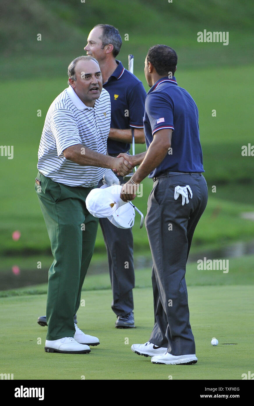 Il team internazionale di stati Angel Cabrera dell Argentina (L) scuote le mani con Stati Uniti i membri del team di Tiger Woods sulla quattordicesima verde dopo la loro fourball corrisponda al 2013 Presidenti Cup a Muirfield Village Golf Club in Dublin, Ohio il 3 ottobre 2013. Cabrera e Marc Leishman dell Australia hanno perso la loro corrispondono a boschi e Matt Kuchar 4. Dopo giovedì l'corrispondenze, gli Stati Uniti conduce da 3,5 a 2,5 punti. UPI/Brian Kersey Foto Stock