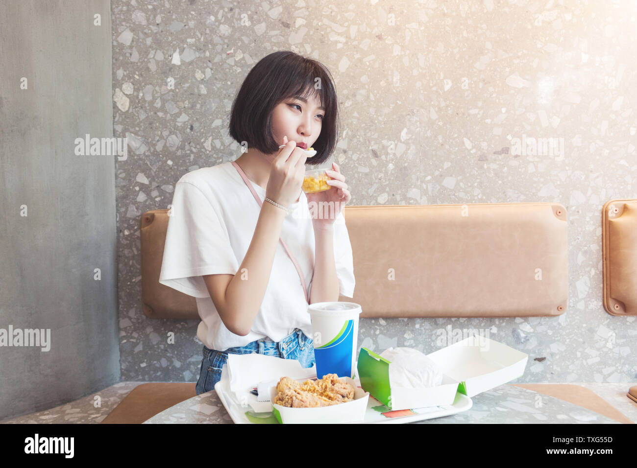 Una ragazza felice di mangiare una tazza di mais in un ristorante. Foto Stock