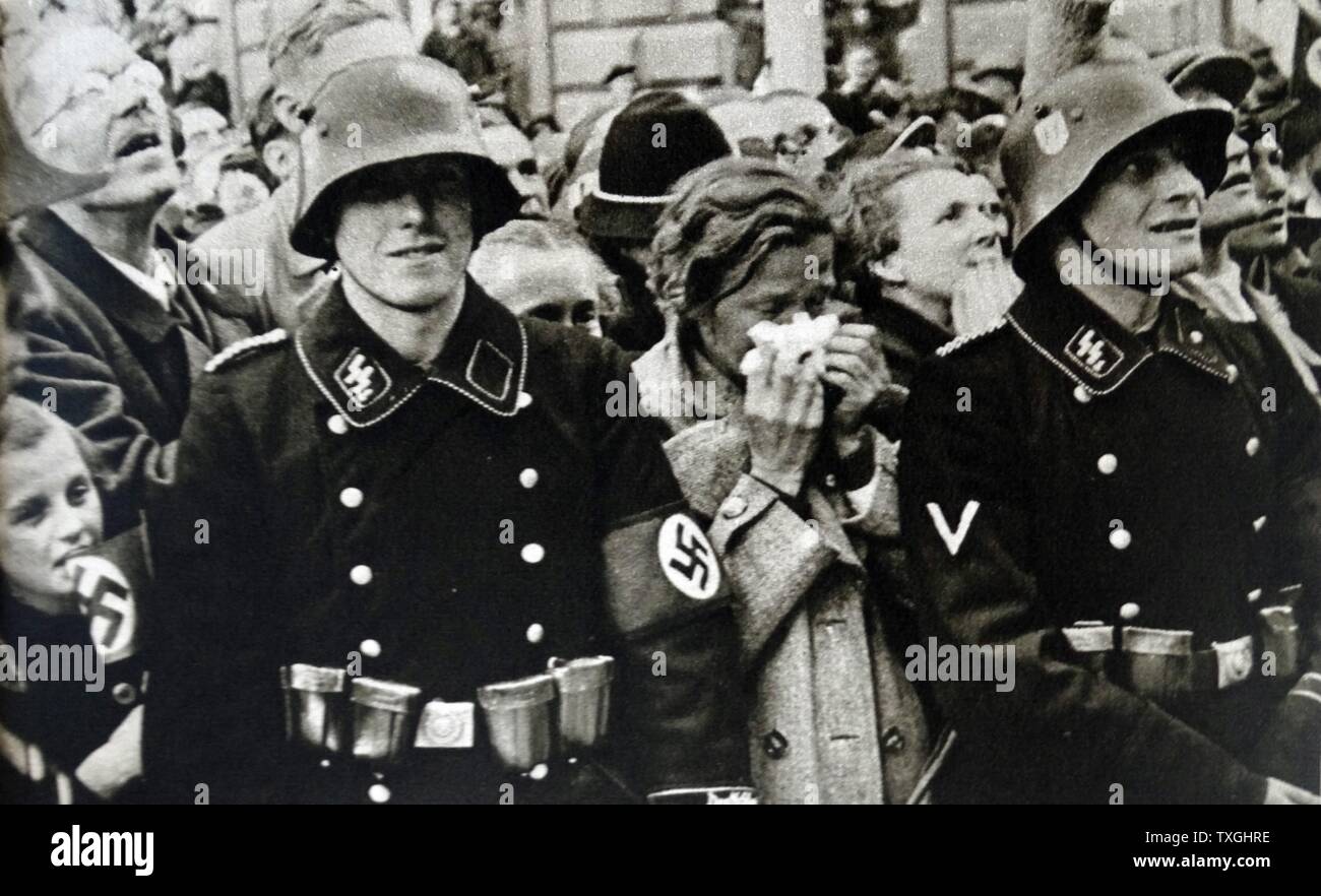 Stampa fotografica di civili austriaci in piedi dietro un S.S. trooper durante l occupazione tedesca di Austria, durante la Seconda Guerra Mondiale. In data xx secolo Foto Stock