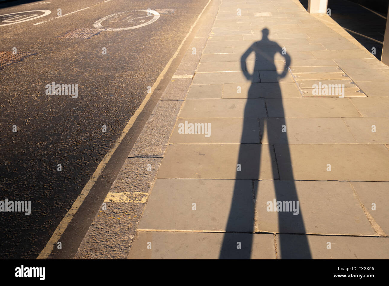 Punto di vista personale ombra di un uomo con le sue mani sulla testa di hips al tramonto di lasciare l'ufficio Foto Stock