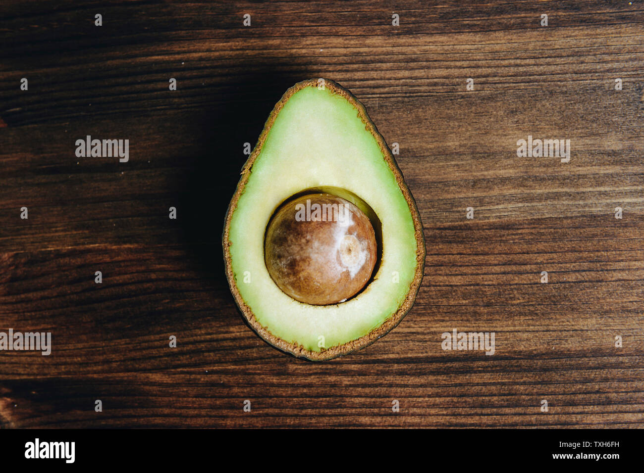 Vista superiore della metà di avocado con sementi sul tavolo di legno, sana cucina vegana concetto con rustico cibo scuro lo stile della foto Foto Stock
