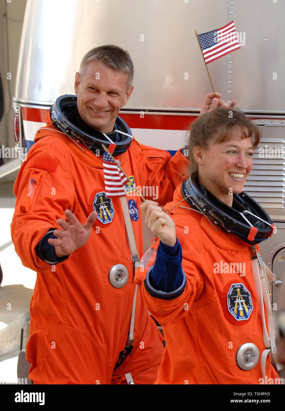 Gli specialisti di missione Lisa Nowak e British-nato Piers Sellers wave bandierine americane come escono delle operazioni e Checkout edificio a bordo della NASA Astrovan in rotta per la navetta spaziale Discovery per la missione STS-121 a Cape Canaveral, in Florida il 4 luglio 2006. (UPI foto/Pat Benic) Foto Stock