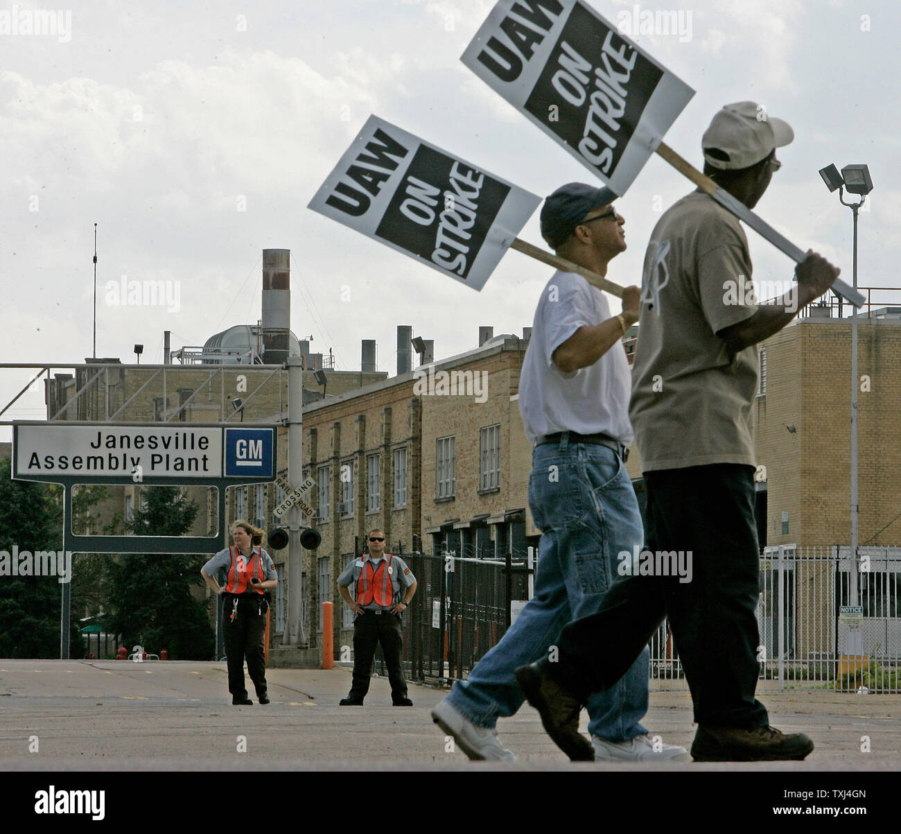 Le guardie di sicurezza guarda come membri di United Auto locale dei lavoratori 95 sciopero alla General Motors impianto di montaggio il 24 settembre 2007 a Janesville, Wisconsin. Citando la sicurezza del posto di lavoro come la parte superiore questione irrisolta la UAW chiamato per un sciopero nazionale contro la GM Lunedì, il primo sciopero nazionale contro l'industria automobilistica degli Stati Uniti dal 1976. (UPI foto/Brian Kersey) Foto Stock