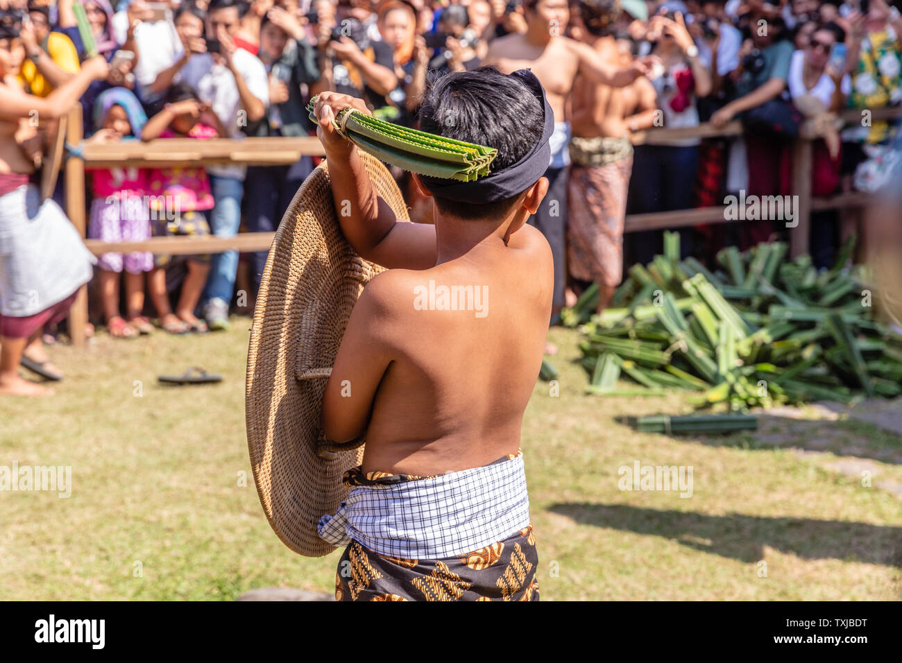 Piccolo ragazzo con foglie di panda preparato per la cerimonia della 'guerra di Pandan' PerangPandan (mekare-kare) a Bali Aga villaggio Tenganan, Karangasem, Bali, Indonesia Foto Stock