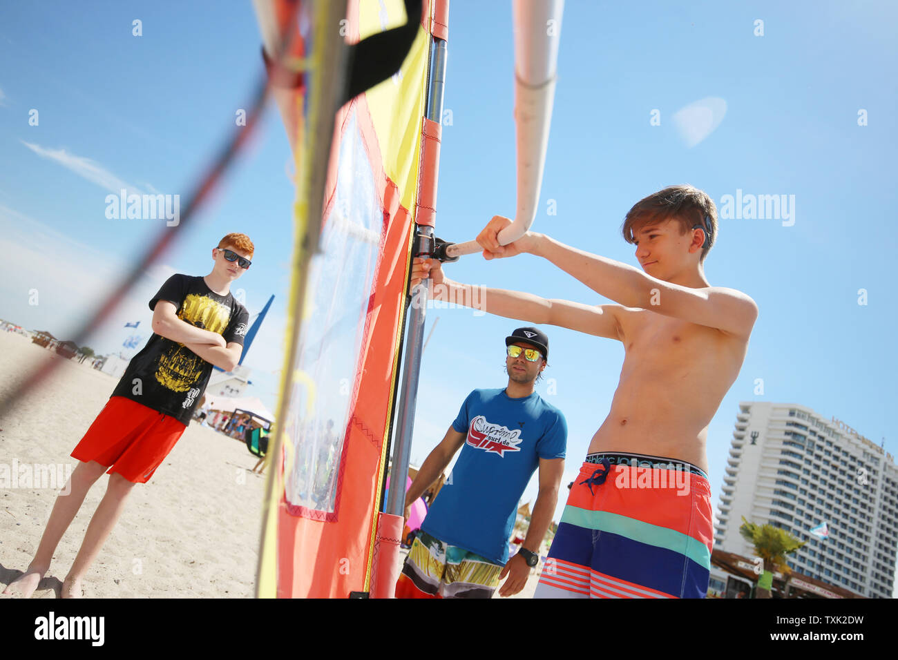 25 giugno 2019, Meclemburgo-Pomerania, Warnemünde: Surf istruttore Tony Dinse (m) offre agli studenti Jan Hermansky (l) e Jonas Heppner (r) un corso di windsurf. La prima spiaggia di Rostock dei giorni di scuola avvengono a Warnemünde beach. I temi principali del progetto giorni includono 'Safe la balneazione " e " Prevenzione della produzione dei rifiuti sulla spiaggia". Foto: Danny Gohlke/dpa Foto Stock