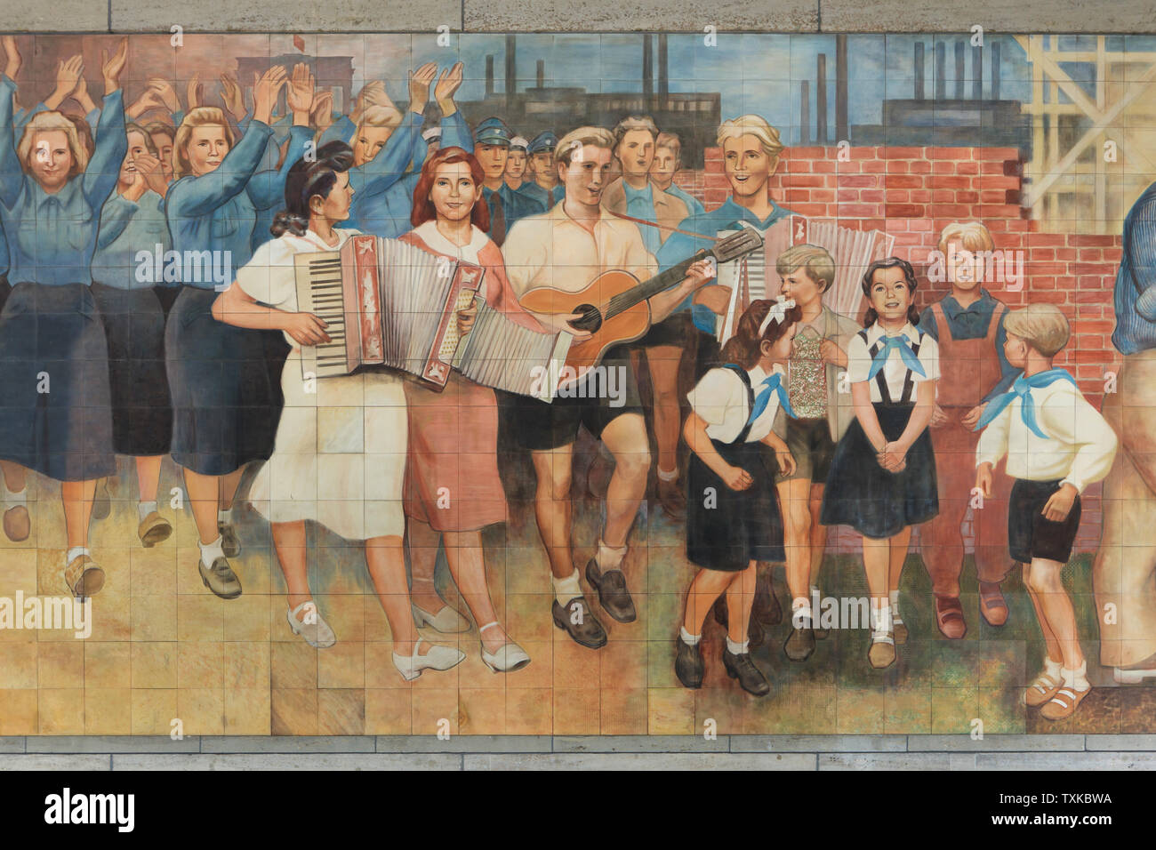 Tedesco orientale pionieri e suonatori raffigurati nel fregio di porcellana "Edificio della repubblica' ('Aufbau der Republik') disegnato dall'artista tedesco Max Lingner (1952-1953) sull'edificio del Consiglio dei ministri della Germania orientale (ex Reichsluftfahrtministerium), ora il Detlev-Rohwedder-Haus a Berlino, Germania. Foto Stock