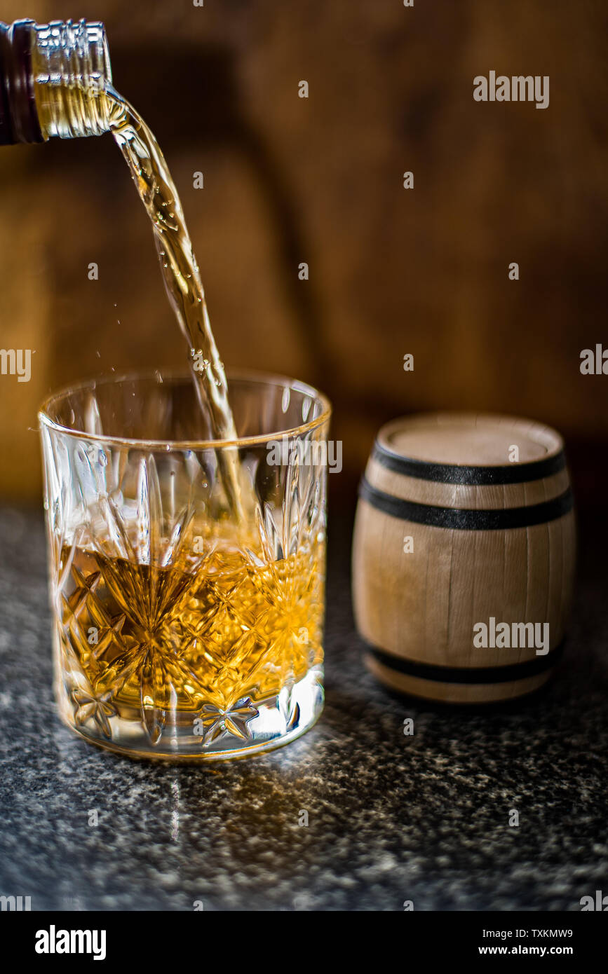 Whisky è versata in un bicchiere con accanto un piccolo barile. Foto Stock